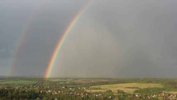Luftaufnahme eines doppelten Regenbogens am Himmel bei Regen, Regenbogen über Dörfern und grünen Feldern — Stockvideo