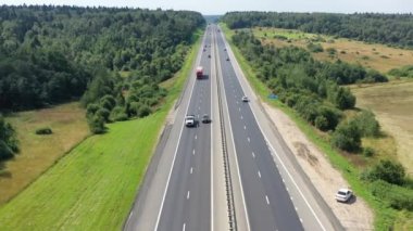 Ormanlar ve tarlalar arasında iki yönlü bir yol üzerinde uçuyor.