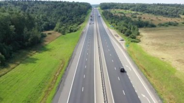 Ormanlar ve tarlalar arasında iki yönlü bir yol üzerinde uçuyor.