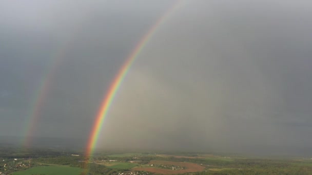 Vista aérea de um arco-íris duplo no céu durante a chuva, arco-íris sobre aldeias e campos verdes — Vídeo de Stock