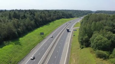 Ormanlar ve tarlalar arasında iki yönlü bir yol üzerinde uçuyor.