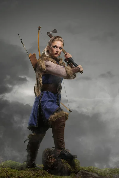Beautiful female viking woman warrior in battle with ax and bow with arrows. Amazon fantasy blonde hair sexy girl