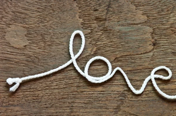 Слово "любовь" написано веревкой на деревянном фоне — стоковое фото