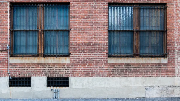 Два окна на кирпичной красной стене — стоковое фото
