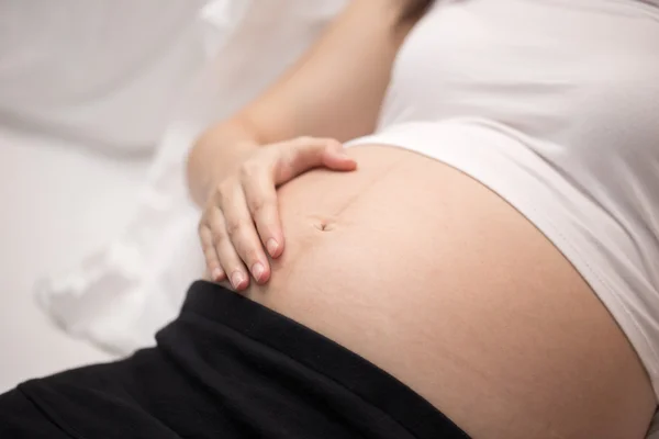 Schwangere berührt ihren Bauch mit der Hand — Stockfoto