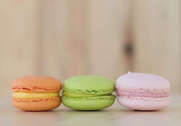 Lezzetli tatlı Macaron, ahşap arka plan üzerinde acıbadem kurabiyesi.