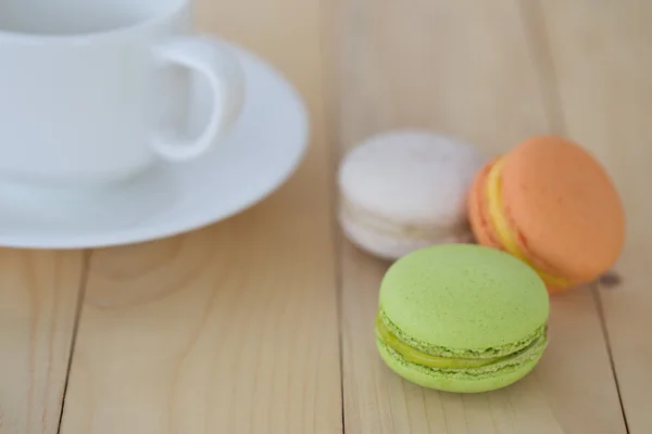 Macaron, ahşap arka plan üzerinde cup ile acıbadem kurabiyesi.