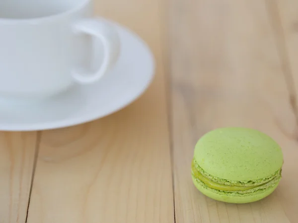 Macaron vert, Macaron avec tasse sur fond bois . — Photo