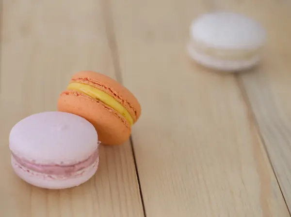 Tatlı turuncu Macaron, ahşap arka plan üzerinde acıbadem kurabiyesi.