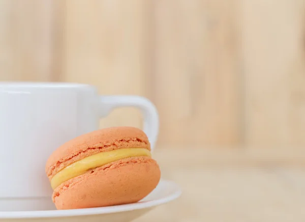 Turuncu Macaron, ahşap arka plan üzerinde cup ile acıbadem kurabiyesi.