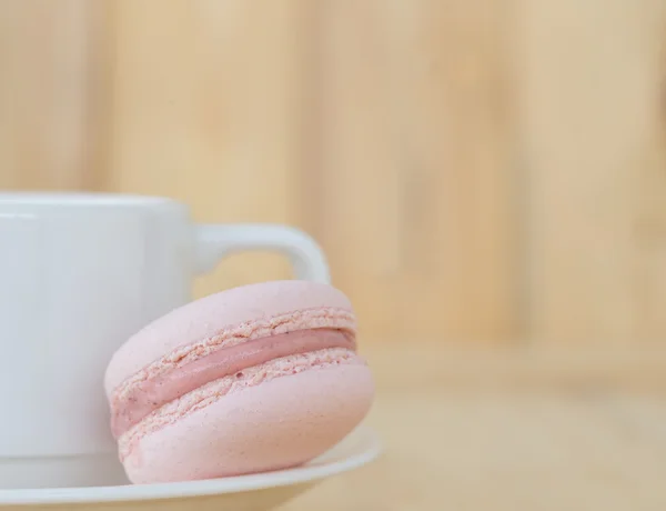 Розовый Macaron, Macaroon с чашкой на деревянном фоне . — стоковое фото
