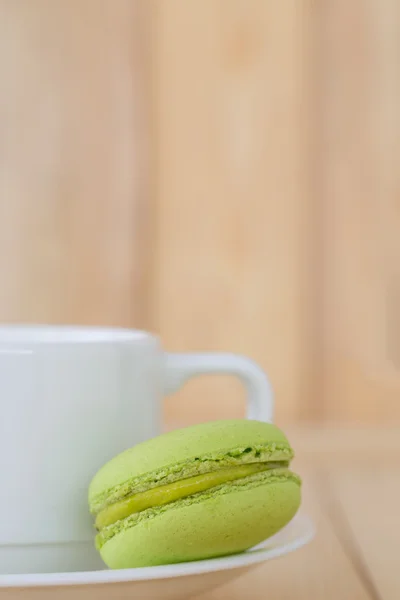 Зеленый Macaron, Macaroon с чашкой на деревянном фоне . — стоковое фото