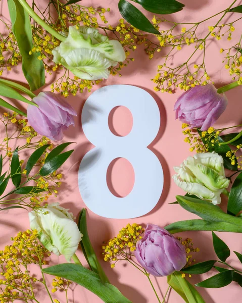 Renkli çiçeklerle pembe arka planda sekiz numara. Düz yatış, üst görünüm.