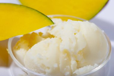 Mango yağı ve taze mango meyvesi yakın plan. Organik kozmetik, cilt bakımı, spa konsepti. Ev yapımı kozmetik ürünleri. Seçici odak.