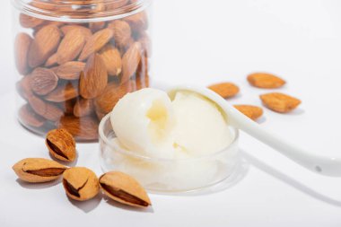 Beyaz arka planda badem ezmesi ve doğal badem. Organik kozmetik, cilt bakımı, spa konsepti. Ev yapımı kozmetik malzemesi.