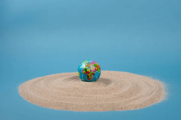 stock image World globe ball on white sand and blue background. Planet earth toy.