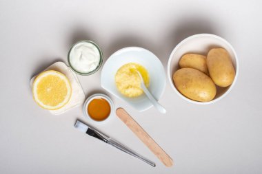 Patates maskesi için malzemeler: Patates, bal, limon, yoğurt. Ev yapımı cilt bakımı ürünü. DIY kozmetik. Düz yatış, üst görünüm.