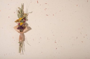 El yapımı kağıt arka planda bir buket kurumuş çiçek. Düz yerde, üst tarafta. Boşluğu kopyala.