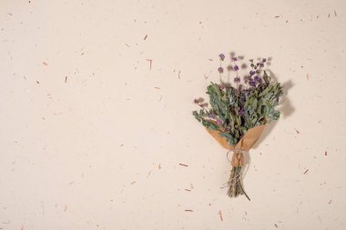 El yapımı kağıt arka planda bir buket kurumuş çiçek. Düz yerde, üst tarafta. Boşluğu kopyala.