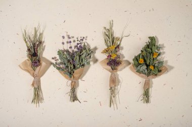 El yapımı kağıt arka planda farklı otlardan oluşan kurumuş bitki demetleri. Düz yatış, üst görünüm.