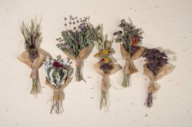 El yapımı kağıt arka planda farklı otlardan oluşan kurumuş bitki demetleri. Düz yatış, üst görünüm.