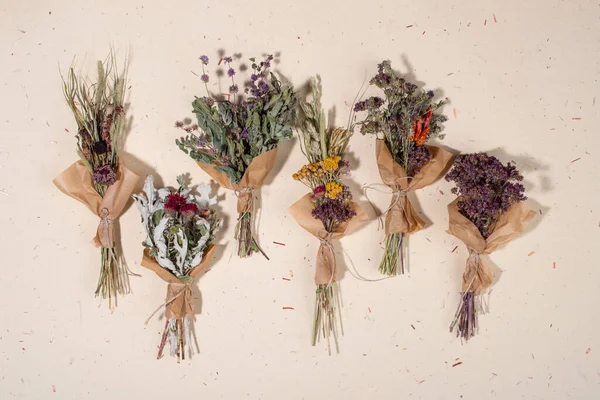 El yapımı kağıt arka planda farklı otlardan oluşan kurumuş bitki demetleri. Düz yatış, üst görünüm.