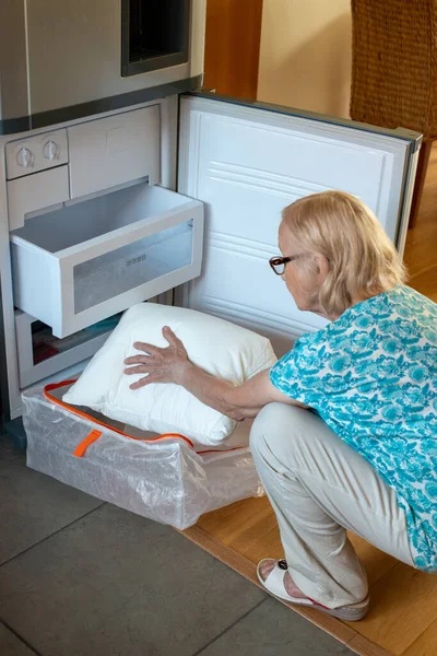 冷蔵庫の冷凍庫に枕を置くシニア女性 暑い時に涼しいままでいる方法 熱を打て — ストック写真