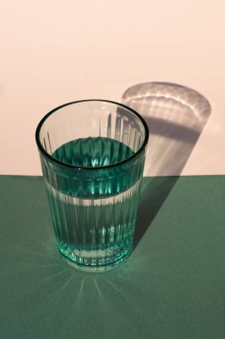 Renkli arka planda sert gölgeli yeşil su camı. Kapat..