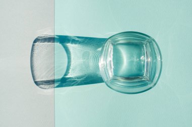 Renkli arka planda sert gölgesi olan yeşil içki bardağı. Kapat..