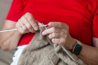 Elinde örgü iğnesi tutan kıdemli bir kadın. Yaşlı nesil hobisi ve aktivite kavramı.
