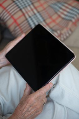 Elinde boş tablet tutan yaşlı bir kadının elleri. Kapatın. Uzayı kopyala, maketle.