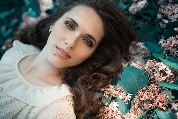 Teen beautiful girl lying on lilac flowers background. Portrait close up. — Stock Photo, Image