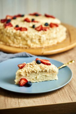 Tabakta bir dilim Napolyon keki. Lezzetli ev yapımı keklerle dolu bir masa. Ahşap arkaplan