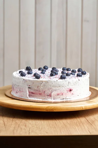 Cake with berries. Board with delicious tasty homemade cake on table. Wooden background.