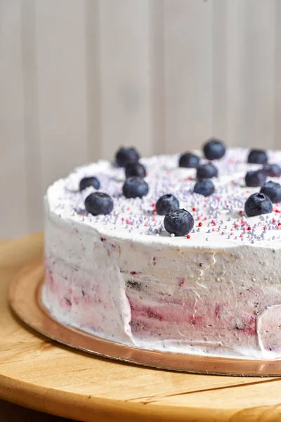 Cake with berries. Board with delicious tasty homemade cake on table. Wooden background.