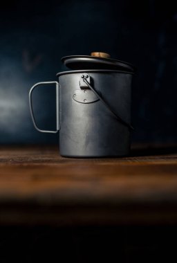 Gri ya da gümüş kahve demliği ahşap bir masada ve siyah bir arka planı var.