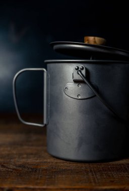 Gri ya da gümüş kahve demliği ahşap bir masada ve siyah bir arka planı var.