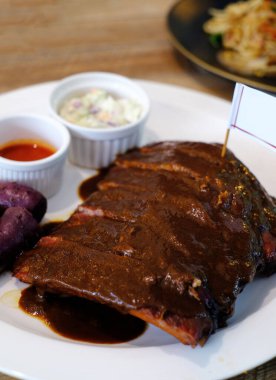 Beyaz tabak üzerinde domuz pirzolası barbeküsü.