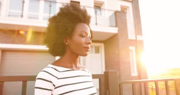 Portrait de belle jeune femme afro-américaine souriante et heureuse avec des cheveux bouclés tournant le visage et regardant la caméra en plein air à la maison Gros plan de jolie fille joyeuse souriant joyeusement sincèrement à la rue — Video