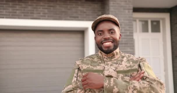 Ritratto di bello felice sorrise soldato afroamericano in cappello e uniforme sorridente alla macchina fotografica e in piedi all'aperto a casa. Un allegro ufficiale maschio dell'esercito che torna. Ragazzo in uniforme. — Video Stock