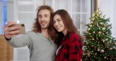 Eğer neşeli beyaz karı ve koca akıllı telefondan canlı yayında konuşuyorsa süslü bir odada ışıldayan yeni yıl ağacının yanında gülümsüyordur. Görüntülü konuşma. Tatil kavramı