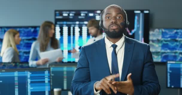 African American man in suit and tie with headset talking to camera and explaining finances market. Trading vlog concept. Trader professional vlogger recording tutorial video. Educative in exchange. — Stock Video