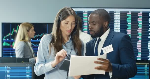 Mixed-races male and female couple of trading co-workers talking and selling or buying stocks with tablet device. African American man and Caucasian woman, traders working in office at exchange market — Stock Video