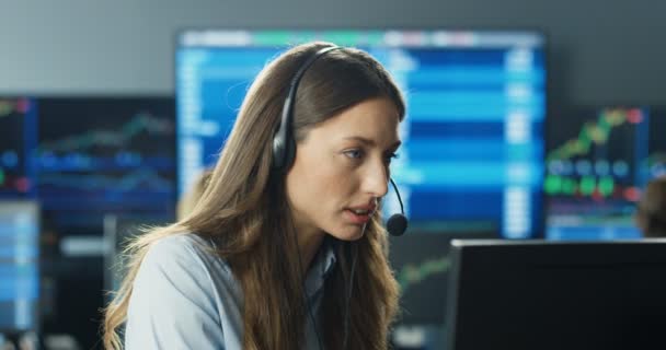 Primer plano de la joven mujer guapa caucásica comerciante en auriculares que trabajan en el monitor de la computadora en la oficina de comercio. La agente está molesta y decepcionada. Pérdida de apuesta y tarifa. Perder dinero en el intercambio. — Vídeo de stock