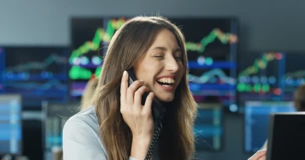 Close up de feliz comerciante mulher caucasiana alegre falando no telefone no escritório e rindo. Boas notícias no mercado de câmbio. Corretora a falar ao telefone e a sorrir. Grande negócio ou transação. — Vídeo de Stock