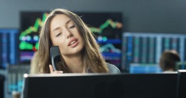 Monitörde çalışan ve telefonlara cevap veren güzel beyaz kadın komisyoncuyu kapatın. Güzel bir borsa simsarı, ticaret ofisinde telefonla konuşuyor..