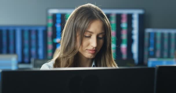 Közelkép a gyönyörű kaukázusi fiatal nő bróker dolgozik monitor számítógép és adatbevitel. Csinos női tőzsdei kereskedő online böngészés és értékesítés vagy vásárlás a kereskedési irodában. — Stock videók