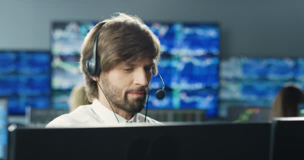 Przystojny, biały młodzieniec w brokerze pracujący na monitorze komputera i rozmawiający z klientem. Mężczyzna giełda handlowiec rozmawia przez telefon w biurze handlowym i sprzedaży. Dział sprzedaży. — Wideo stockowe