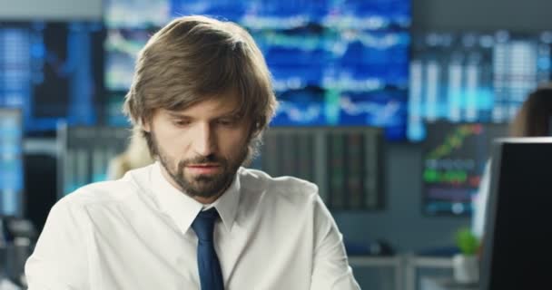 Close-up van de jonge blanke knappe mannelijke makelaar in stropdas zittend in het kantoor voor de computer en met hard werkende -dag. Moe van een depressieve belegger of handelaar met problemen en moeilijkheden. — Stockvideo