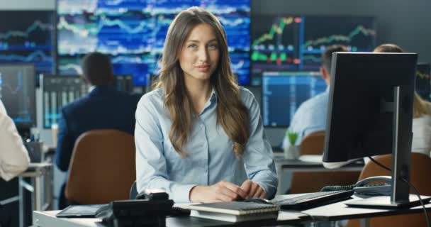 Ritratto di giovane donna caucasica bella commerciante che lavora al computer, poi guardando la macchina fotografica e sorridendo in ufficio commerciale di borsa di scambio. Broker femminile di successo con sorriso sul viso. — Video Stock